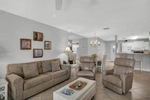 a living room with a couch and chairs and a kitchen at Seabreeze Escape in Destin