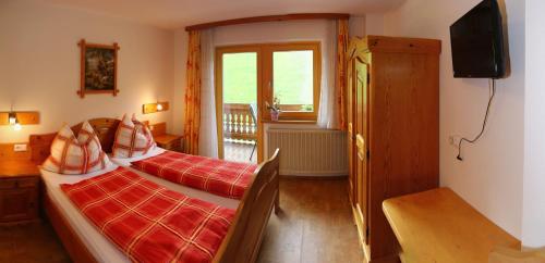 a bedroom with two beds and a television and a window at Haus Harmonika in Ramsau am Dachstein