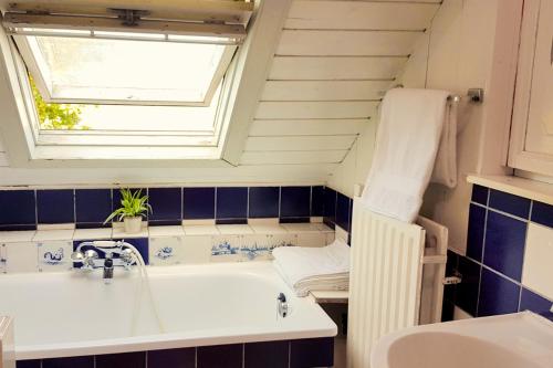 a bathroom with a tub and a sink and a window at Countryside Bliss: Historic Cottage by the Sea in Burgh Haamstede