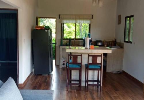 a kitchen with a refrigerator and a table with stools at Villa Marina, Nosara in Río Seco