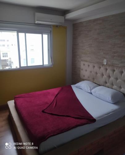 een slaapkamer met een groot bed en een raam bij Flat central dois quartos in Guaporé