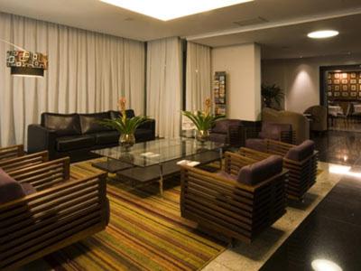 una gran sala de estar con sofás y una mesa. en Hotel de luxo BH, en Belo Horizonte