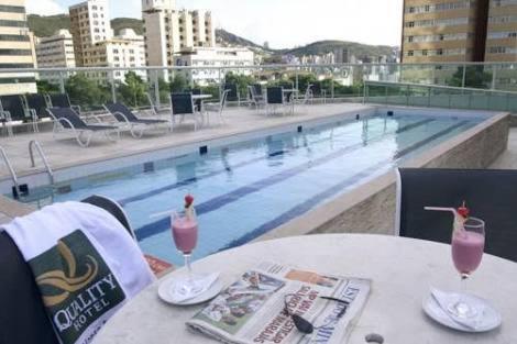 una mesa con dos copas de vino y una piscina en Hotel de luxo BH, en Belo Horizonte