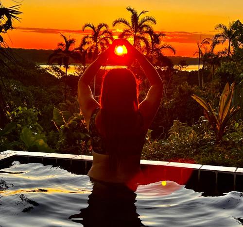uma mulher numa piscina com um pôr-do-sol em Reserva Natural Natura Park em Puerto Nariño