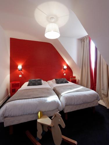 a bedroom with two beds and a red wall at Hôtel La Résidence des Artistes in Roscoff