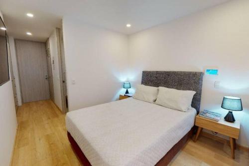 1 dormitorio con 1 cama blanca grande y 2 lámparas en Apartamento con Terraza cerca a Unicentro, en Bogotá