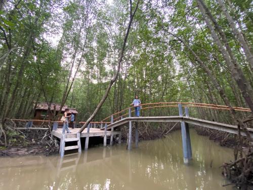 two people standing on a bridge over a body of water at Homestay Hải Nam Đất Mũi in Xóm Mũi