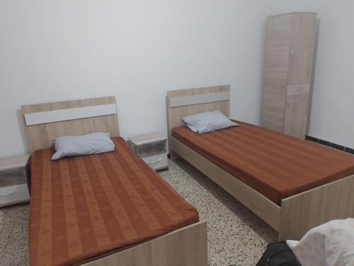 two beds are in a room withermottermottermott at Meilleure Escale à Gabes in Al Mayyitah