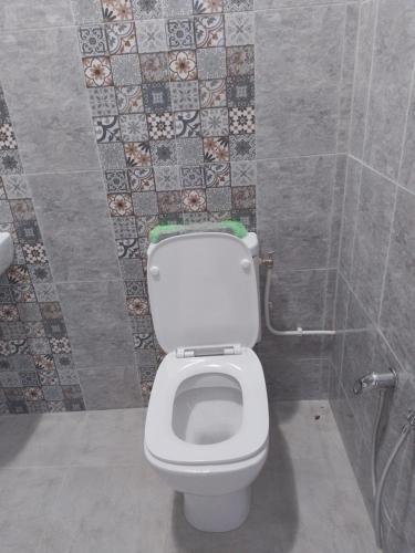 a bathroom with a toilet and a tile wall at Meilleure Escale à Gabes in Al Mayyitah