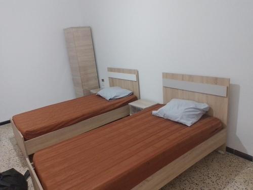 two wooden beds in a room with a mirror at Meilleure Escale à Gabes in Al Mayyitah