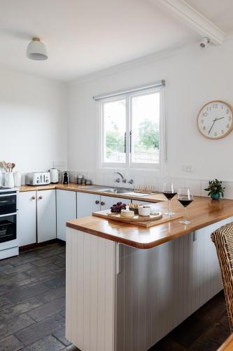 a kitchen with white cabinets and a clock on the wall at Saltwood in Bridport