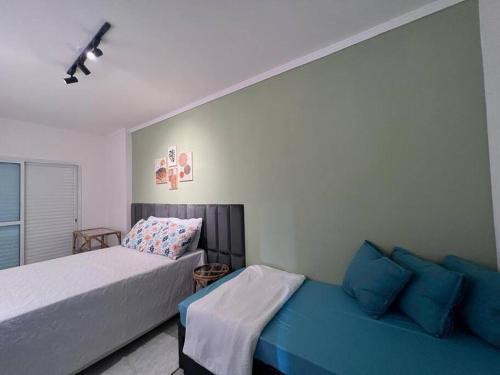 - une chambre avec 2 lits et un canapé bleu dans l'établissement AP alto padrão no Caiçara, à Praia Grande