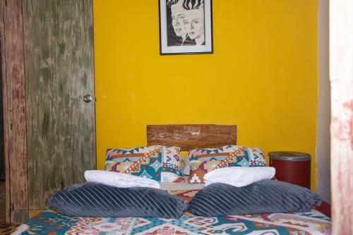 a bed with two pillows and a yellow wall at Hostal Macondo Inn in Carmen de Viboral
