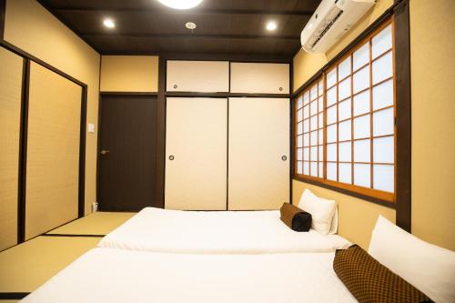 um pequeno quarto com duas camas e duas janelas em 東雲庵/shinonomean em Quioto