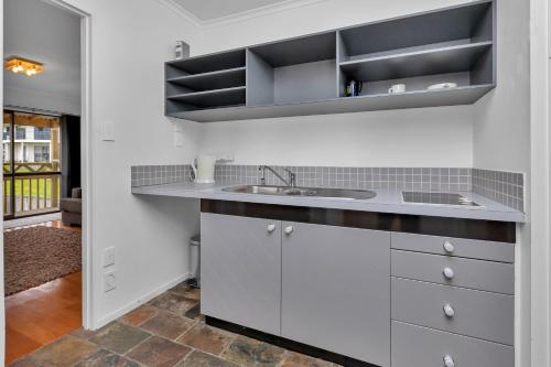 a kitchen with white cabinets and a sink at Seaside on Stratford - Cable Bay Holiday Home in Cable Bay