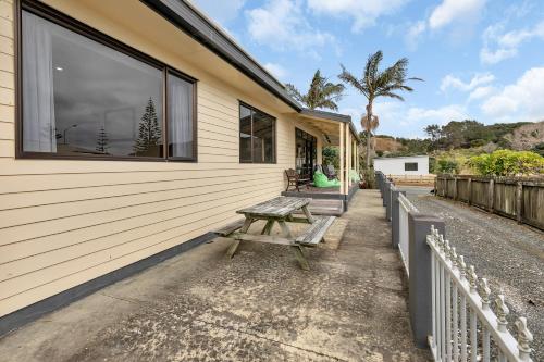 a picnic table sits outside of a house at Seaside on Stratford - Cable Bay Holiday Home in Cable Bay