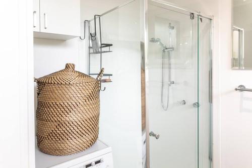 uma casa de banho com uma cabina de duche ao nível do chão e uma cesta. em Beachside Gem in Ocean Grove em Ocean Grove