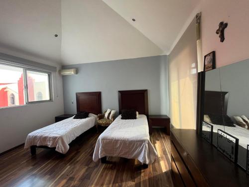 a room with two beds and a large window at Casa Serena - Casa de Huéspedes in Guadalajara