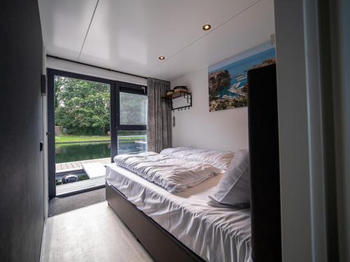 1 dormitorio con 2 camas y ventana en Luxury houseboat with beautiful views over the Mookerplas, en Middelaar