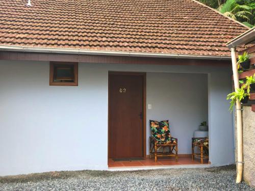 a house with a door and a chair on a porch at Residência Vô José - Casa 02 in Pomerode