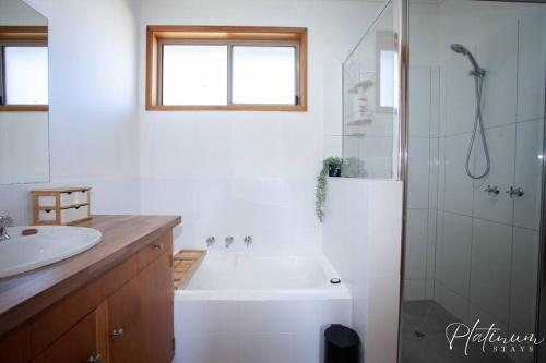 a bathroom with a tub and a sink and a shower at Glenare on Read in Horsham