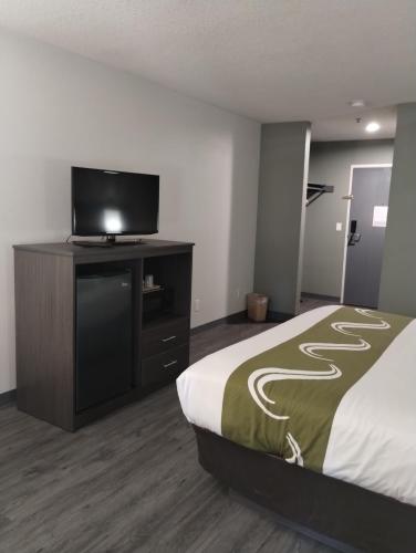 a hotel room with a bed and a flat screen tv at Quality Inn & Suites Wilsonville in Wilsonville