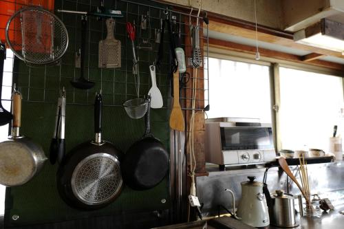 a kitchen with pots and pans hanging on the wall at 魚の宿【海と西】 