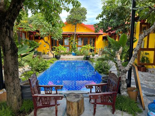 uma piscina num quintal com cadeiras e uma casa em La Belle Anbang Homestay em Hoi An