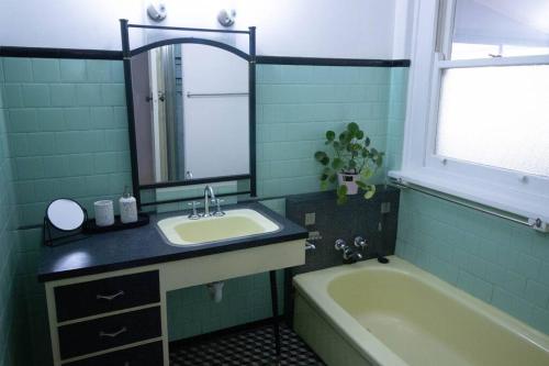y baño con lavabo, bañera y espejo. en • Parkside • Spacious central family retreat en Alfredton