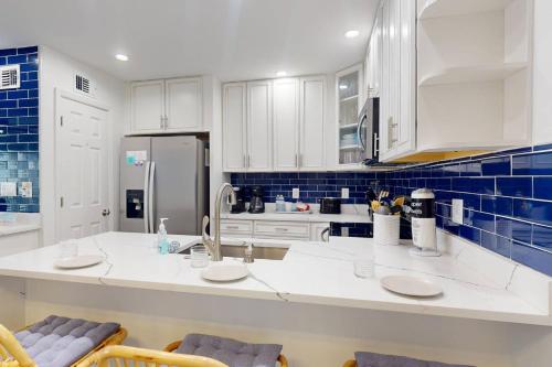 a kitchen with white cabinets and blue tiles at 247-B - Madeira Beach Yacht Club in St. Pete Beach