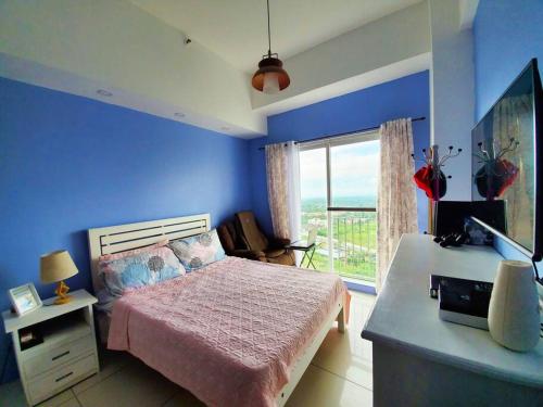 a blue bedroom with a bed and a large window at Sofias Place w/ Massagechair in Tagaytay