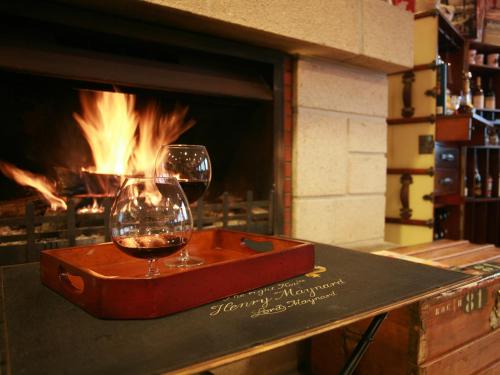 two glasses of wine sitting on a table in front of a fireplace at Hôtel La Résidence des Artistes in Roscoff