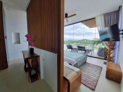 a bedroom with a bed and a view of a living room at Magic suites Seaview villas, Koh Samui in Choeng Mon Beach