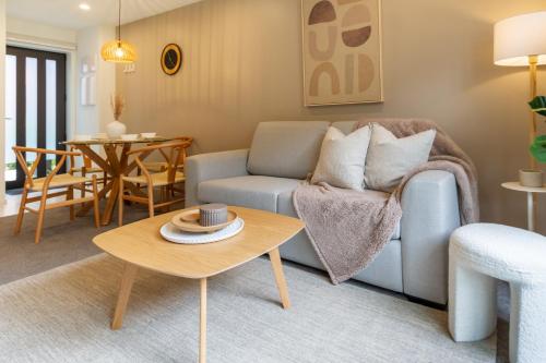 uma sala de estar com um sofá e uma mesa em Gorgeous Getaway on Gloucester St- 1 Bed 1 Bath em Christchurch