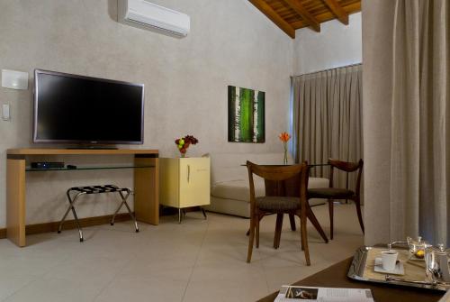 a living room with a flat screen tv and chairs at Abayomi Hotel in Ilhabela