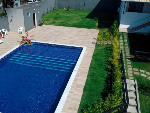 an overhead view of a swimming pool with two people sitting next to it at Pousada Jardins - Mar Grande in Vera Cruz de Itaparica