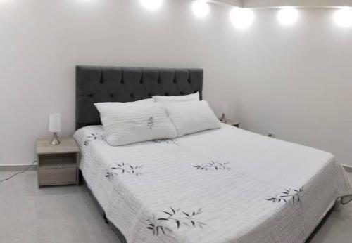 een slaapkamer met een wit bed met een zwart hoofdeinde bij Encantador Apto Con Aire in Neiva