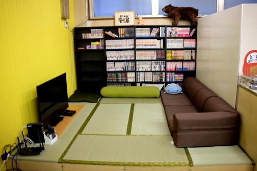 a living room with a couch and a shelf of books at Hostel Furoya in Osaka