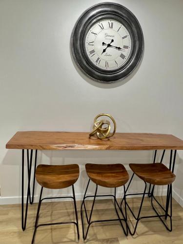 a table with four chairs and a clock on the wall at Vinash Luxury Suite in Edmonton