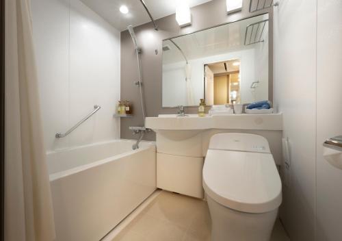 a bathroom with a toilet and a sink and a mirror at Meitetsu Komaki Hotel in Komaki