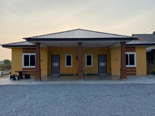 a yellow building with a picnic table in front of it at Anak Air Homestay, Serkam Islam Guest Only in Malacca