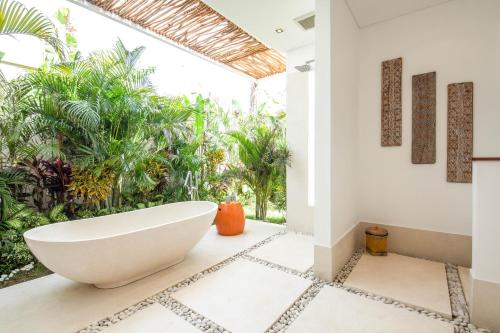 a bath tub in a bathroom with plants at Dreamy 5br Haven, 200m To Berawa's Blissful Beach in Canggu