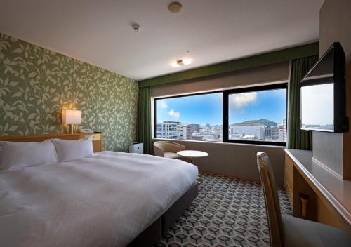 小牧市にある名鉄小牧ホテルのベッドと大きな窓が備わるホテルルームです。