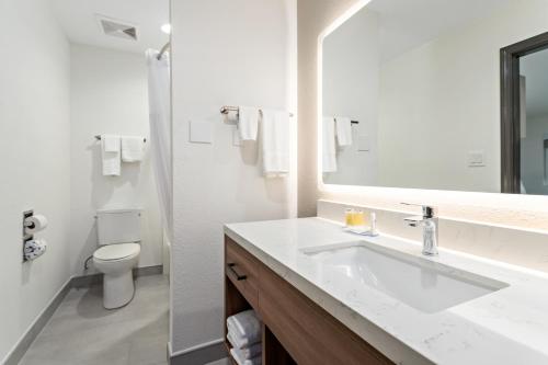 a bathroom with a sink and a toilet and a mirror at Baymont by Wyndham Beaumont in Beaumont