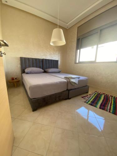 - une chambre avec un lit et une grande fenêtre dans l'établissement Appartement Dahomey Bouznika, à Bouznika