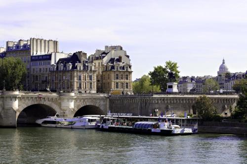a boat traveling down a river next to a bridge at Hotel Ducs de Bourgogne in Paris