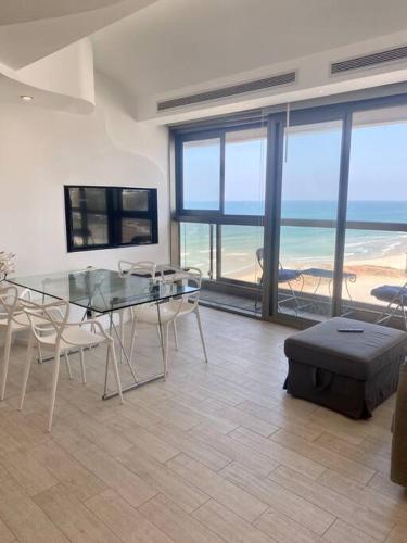 uma sala de jantar com uma mesa de vidro e vista para o oceano em ruth’s balcony sea view apt em Herzliya B
