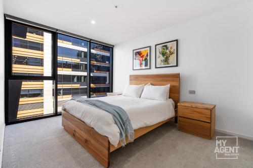 een slaapkamer met een groot bed en grote ramen bij Spectacular Victoria Harbour Apartment Docklands in Melbourne