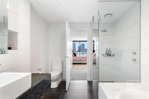 een witte badkamer met een toilet en een wastafel bij Spectacular Victoria Harbour Apartment Docklands in Melbourne