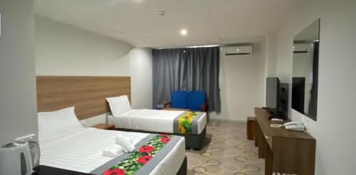 a hotel room with two beds and a television at Vualiku Hotel & Apartments in Nadi